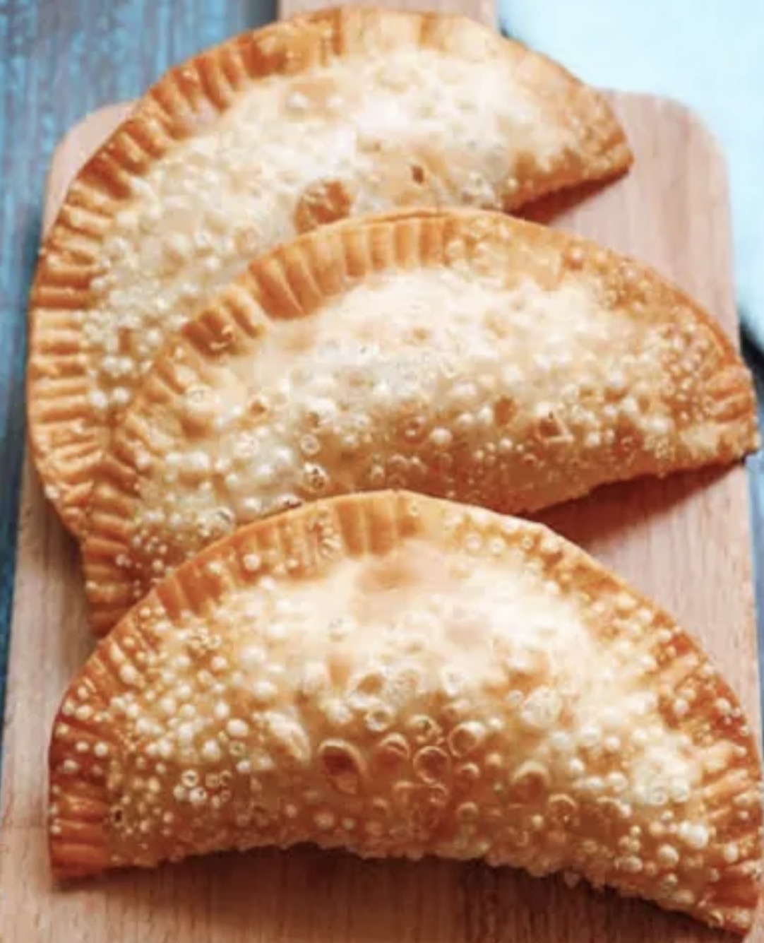 Golden empanadas on a wooden serving board